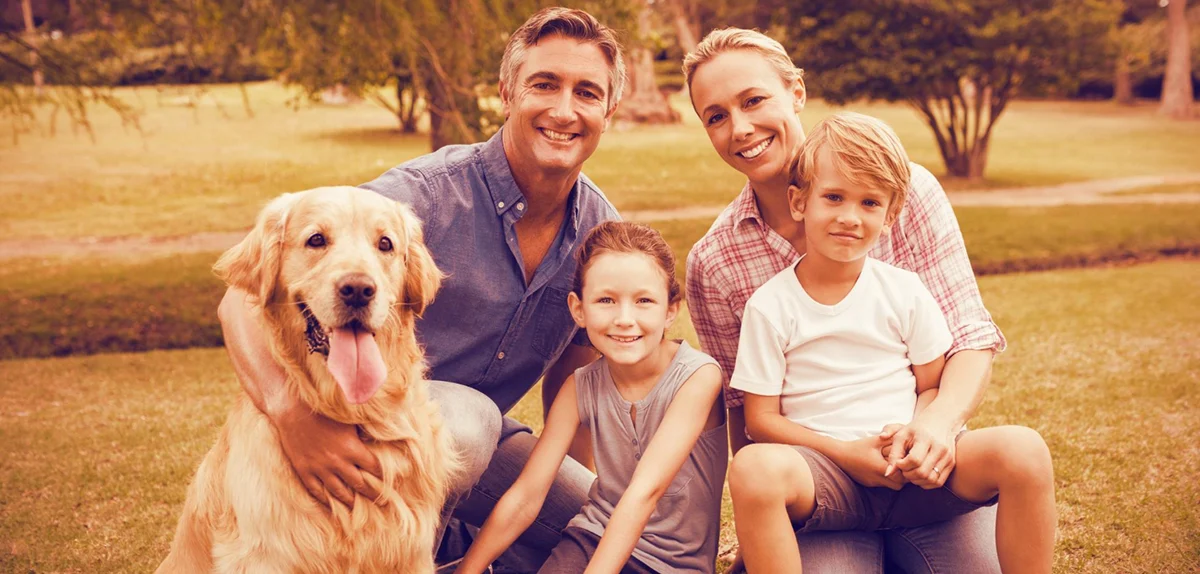 matrimoni joven con dos hijos y su perro golden retriver felices en un parque